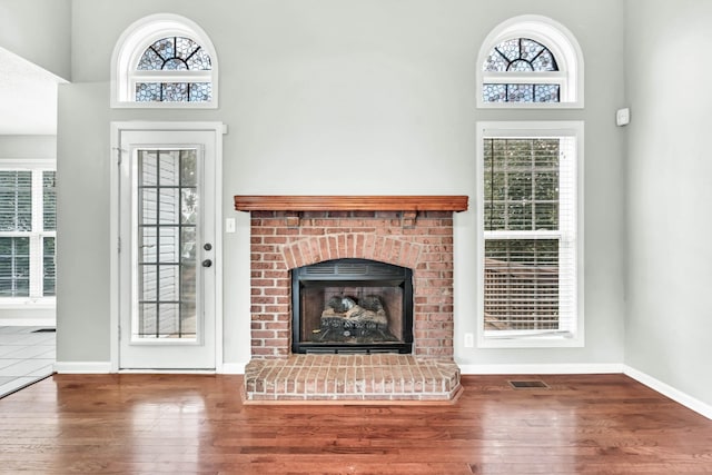 720 Superior Ln, Clarksville, TN 37043 - unfurnished living room with wood finished floors, plenty of natural light, a brick fireplace, and a high ceiling