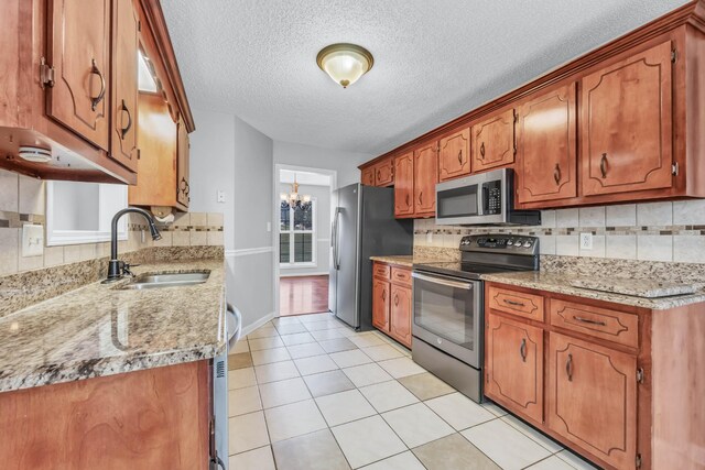 720 Superior Ln, Clarksville, TN 37043 - kitchen featuring appliances with stainless steel finishes, a chandelier, backsplash, brown cabinets, and a textured ceiling