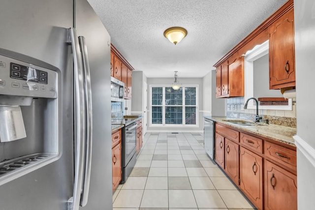 720 Superior Ln, Clarksville, TN 37043 - kitchen featuring appliances with stainless steel finishes, brown cabinetry, light tile patterned floors, a textured ceiling, and hanging light fixtures