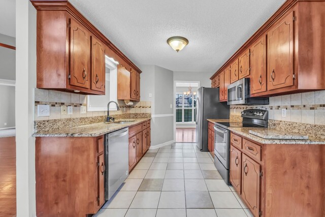 720 Superior Ln, Clarksville, TN 37043 - kitchen with stainless steel appliances, tasteful backsplash, light tile patterned floors, brown cabinetry, and a textured ceiling