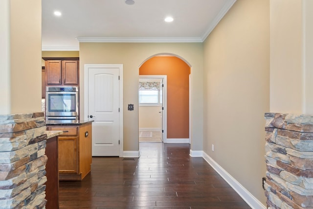 5010 Moretto Ct, Spring Hill, TN 37174 - kitchen with oven, arched walkways, dark wood-type flooring, crown molding, and brown cabinetry