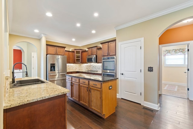 5010 Moretto Ct, Spring Hill, TN 37174 - kitchen with appliances with stainless steel finishes, light stone counters, arched walkways, decorative backsplash, and a kitchen island