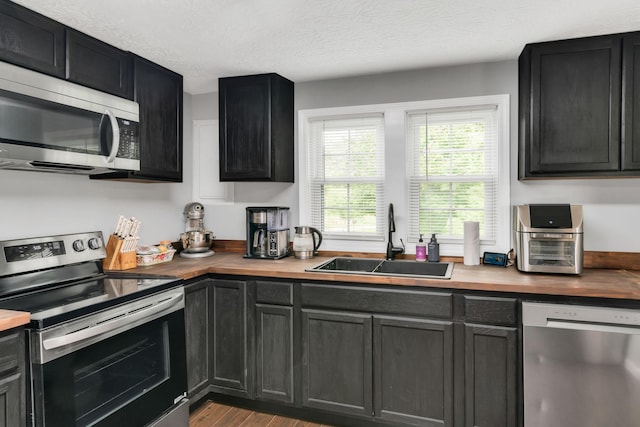 2750 Clampit Hollow Rd, Lafayette, TN 37083 - kitchen featuring stainless steel appliances, wooden counters, wood finished floors, a textured ceiling, and dark cabinetry