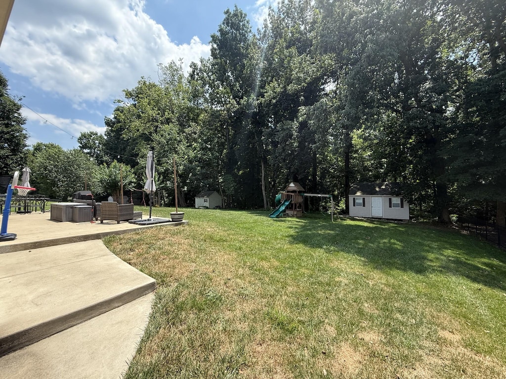 4392 Taylor Hall Ln, Adams, TN 37010 - view of grassy yard featuring a storage unit, a playground, and a patio