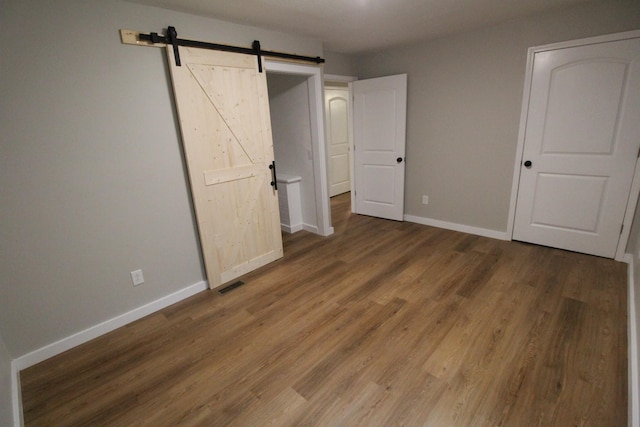 61 Kentucky Dr, Cadiz, KY 42211 - unfurnished bedroom featuring a barn door and wood finished floors