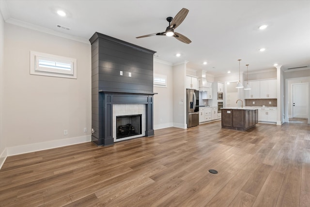 2620 Buckner Ln, Thompsons Station, TN 37179 - unfurnished living room featuring a ceiling fan, ornamental molding, a large fireplace, light wood-style floors, and recessed lighting