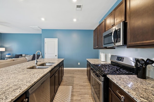 2305 Madeline Ct, Columbia, TN 38401 - kitchen with stainless steel appliances, light wood-type flooring, tasteful backsplash, dark brown cabinets, and light stone countertops