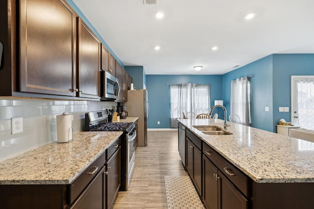 2305 Madeline Ct, Columbia, TN 38401 - kitchen with stainless steel appliances, light wood-type flooring, an island with sink, tasteful backsplash, and healthy amount of natural light