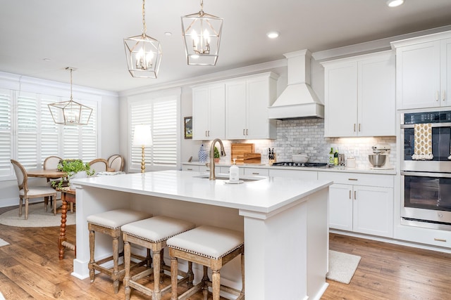 2744 Morrow Ln, Columbia, TN 38401 - kitchen featuring appliances with stainless steel finishes, custom exhaust hood, light countertops, a breakfast bar area, and a chandelier