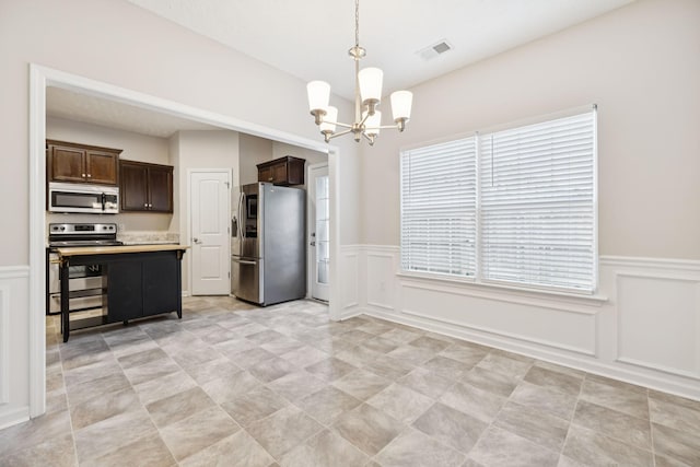 2306 New Holland Cir, Murfreesboro, TN 37128 - kitchen with stainless steel appliances, a decorative wall, a chandelier, dark brown cabinetry, and wainscoting