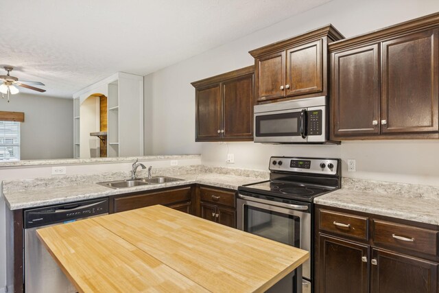 2306 New Holland Cir, Murfreesboro, TN 37128 - kitchen with appliances with stainless steel finishes, butcher block counters, dark brown cabinets, a ceiling fan, and a peninsula