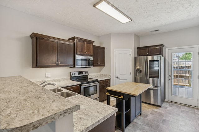 2306 New Holland Cir, Murfreesboro, TN 37128 - kitchen with stainless steel appliances, dark brown cabinetry, a textured ceiling, a peninsula, and wood counters