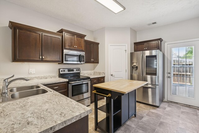 2306 New Holland Cir, Murfreesboro, TN 37128 - kitchen with stainless steel appliances, dark brown cabinetry, butcher block countertops, a textured ceiling, and open shelves
