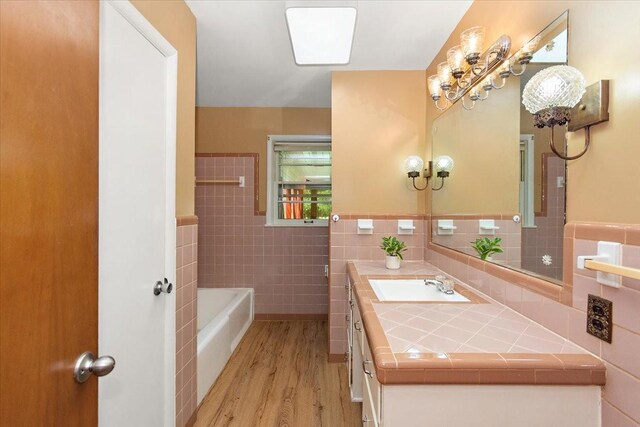 318 David St, Lawrenceburg, TN 38464 - bathroom featuring tile walls, a garden tub, wood finished floors, vanity, and a wainscoted wall