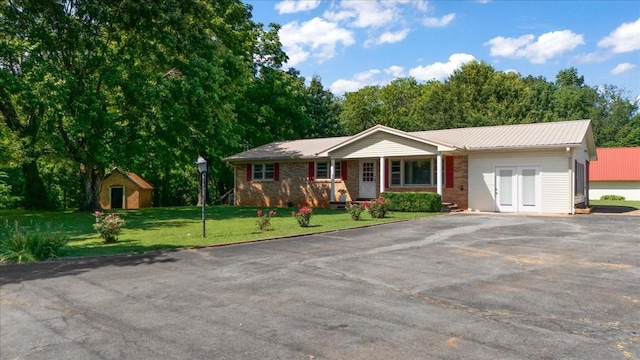 318 David St, Lawrenceburg, TN 38464 - ranch-style house featuring asphalt driveway, a front yard, a porch, a metal roof, and a shed