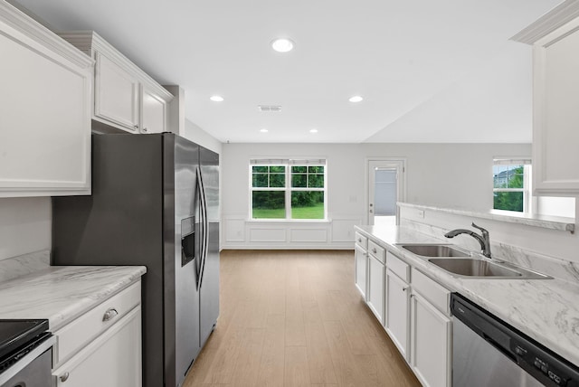 2149 Longhunter Chase Dr, Spring Hill, TN 37174 - kitchen with stainless steel appliances, light wood-style floors, a wainscoted wall, white cabinetry, and healthy amount of natural light