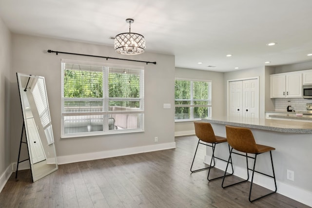 808 Garrett Way Ct, Antioch, TN 37013 - kitchen featuring stainless steel microwave, white cabinetry, a kitchen bar, light stone countertops, and dark wood-style flooring