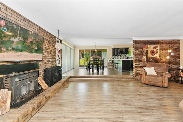 19 Horseshoe Bend Rd, Leoma, TN 38468 - unfurnished living room featuring wood finished floors, brick wall, ornamental molding, and a wood stove