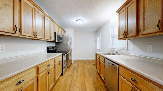 4321 Lynchburg Rd, Winchester, TN 37398 - kitchen featuring appliances with stainless steel finishes, light wood-style floors, light countertops, a textured ceiling, and brown cabinetry