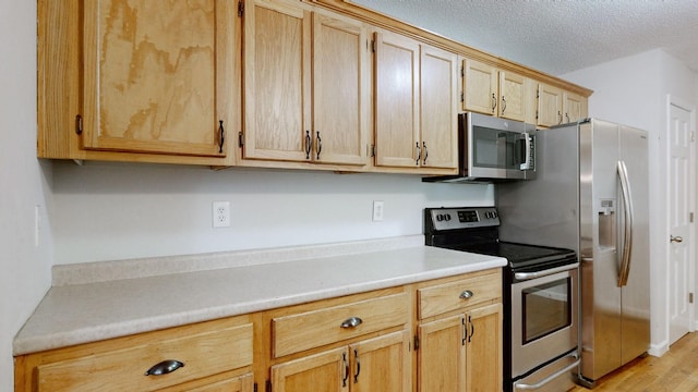 4321 Lynchburg Rd, Winchester, TN 37398 - kitchen featuring appliances with stainless steel finishes, light countertops, light brown cabinetry, and a textured ceiling