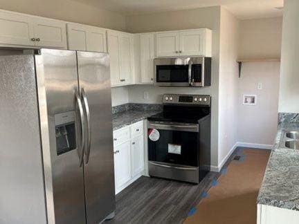 484 Meadowbrook Dr, Mcminnville, TN 37110 - kitchen with appliances with stainless steel finishes, white cabinets, stone counters, and dark wood-type flooring