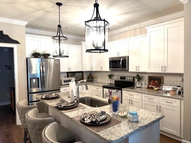 967 Horse Mountain Rd Unit 1E, Shelbyville, TN 37160 - kitchen featuring stainless steel appliances, white cabinetry, a kitchen bar, light stone counters, and decorative backsplash