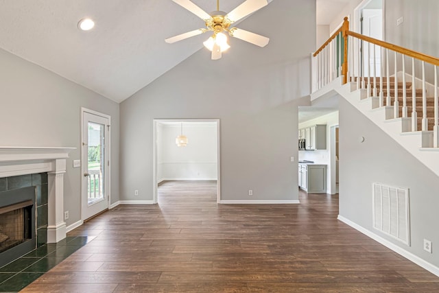 2415 Franklin Ln, Murfreesboro, TN 37130 - unfurnished living room featuring high vaulted ceiling, a tile fireplace, dark wood-style flooring, ceiling fan, and stairs