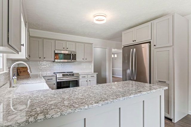 2415 Franklin Ln, Murfreesboro, TN 37130 - kitchen featuring stainless steel appliances, decorative backsplash, a peninsula, light stone counters, and crown molding