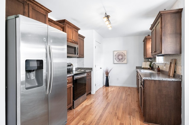 7566 S Swift Rd, Goodlettsville, TN 37072 - kitchen with appliances with stainless steel finishes, tasteful backsplash, light wood finished floors, and dark countertops