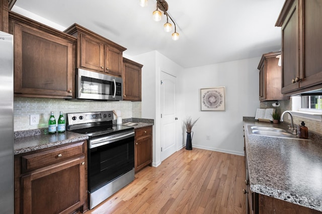 7566 S Swift Rd, Goodlettsville, TN 37072 - kitchen with stainless steel appliances, dark countertops, tasteful backsplash, light wood-style floors, and dark brown cabinetry