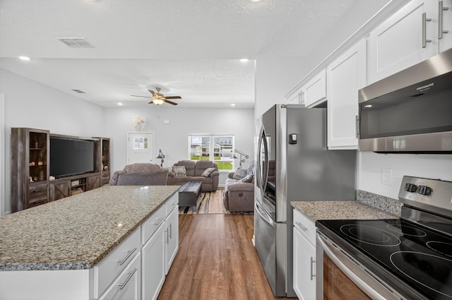 77 Frost St, Decherd, TN 37324 - kitchen featuring appliances with stainless steel finishes, dark wood-style flooring, white cabinets, light stone counters, and open floor plan