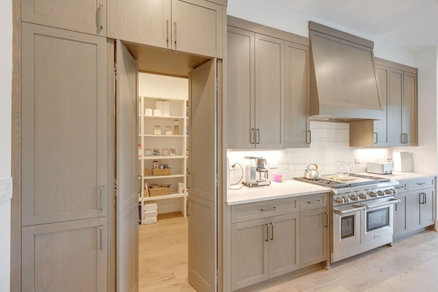 7555 Whiskey Rd, College Grove, TN 37046 - kitchen with range with two ovens, premium range hood, light wood-style flooring, light countertops, and gray cabinets