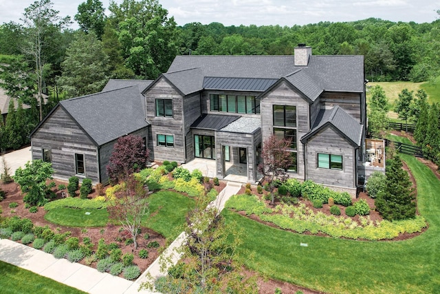 7555 Whiskey Rd, College Grove, TN 37046 - contemporary home with a standing seam roof, a chimney, a metal roof, a front lawn, and a forest view