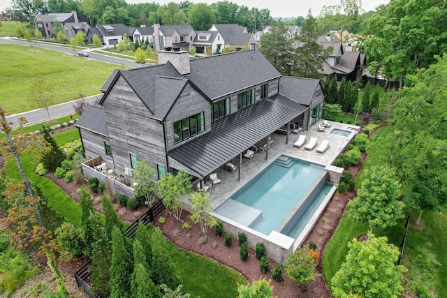 7555 Whiskey Rd, College Grove, TN 37046 - back of property with an infinity pool, a standing seam roof, a patio area, a yard, and a chimney