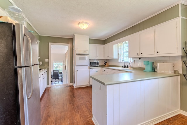 996 Matrose Carrolls Rd, Michie, TN 38357 - kitchen with stainless steel appliances, wood finished floors, ornamental molding, a peninsula, and white cabinetry