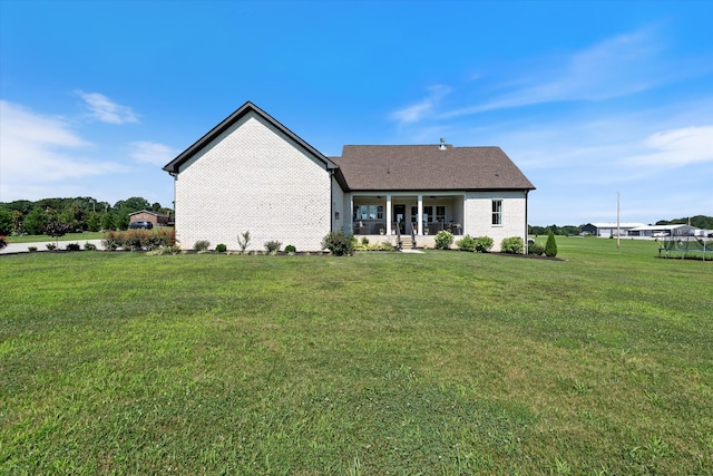 2157 Abiff Rd, Burns, TN 37029 - back of property with a lawn, a trampoline, brick siding, and a patio area