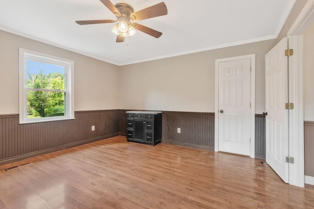 3035 Culleoka Hwy, Culleoka, TN 38451 - empty room featuring wainscoting, light wood finished floors, ceiling fan, and crown molding