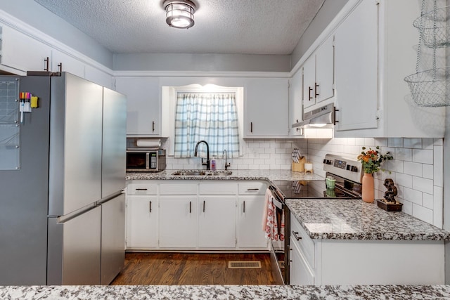 528 Maple St, Pulaski, TN 38478 - kitchen featuring stainless steel appliances, under cabinet range hood, dark wood-style flooring, a textured ceiling, and white cabinetry