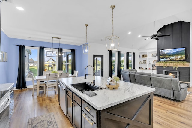 426 Maple Bend Rd, Winchester, TN 37398 - kitchen featuring stainless steel dishwasher, light wood-type flooring, a lit fireplace, a center island with sink, and ceiling fan