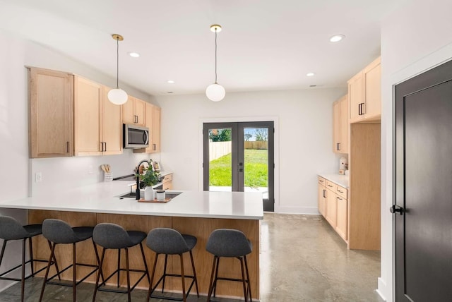 1823 River Dr, Nashville, TN 37218 - kitchen featuring stainless steel microwave, light brown cabinetry, a peninsula, finished concrete floors, and french doors