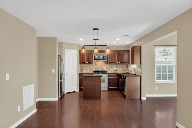 2008 Kingston Pl, Spring Hill, TN 37174 - kitchen with stainless steel appliances, dark countertops, a kitchen island, backsplash, and dark wood finished floors