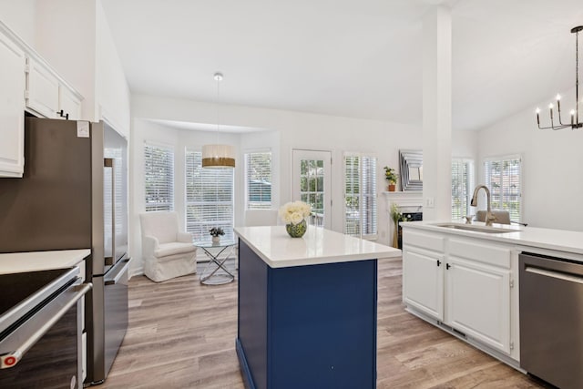 201 Hideaway Trl, Franklin, TN 37069 - kitchen with appliances with stainless steel finishes, a kitchen island, light wood finished floors, a fireplace, and vaulted ceiling