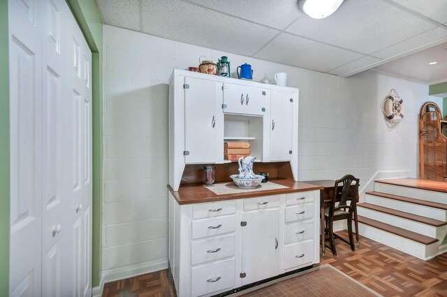 20151 Ben Fly Rd, Lyles, TN 37098 - kitchen featuring concrete block wall, white cabinetry, and a drop ceiling