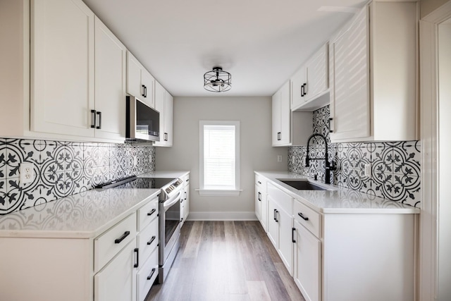 7365 Coldwater Rd, Fairview, TN 37062 - kitchen featuring appliances with stainless steel finishes, light countertops, decorative backsplash, light wood-style floors, and white cabinetry