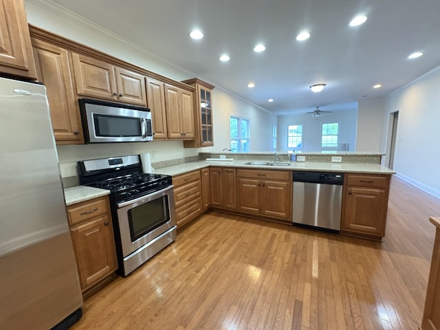 111 Reeds Ln, Sewanee, TN 37375 - kitchen featuring appliances with stainless steel finishes, light wood-style flooring, ornamental molding, a peninsula, and brown cabinets