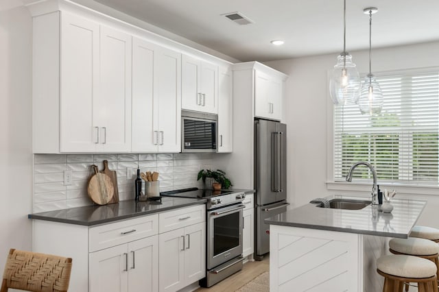 700 N Dupont Ave Unit 207, Madison, TN 37115 - kitchen featuring appliances with stainless steel finishes, tasteful backsplash, a kitchen breakfast bar, light wood-type flooring, and white cabinets