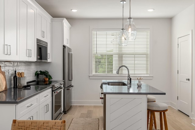700 N Dupont Ave Unit 207, Madison, TN 37115 - kitchen featuring appliances with stainless steel finishes, light wood-style flooring, tasteful backsplash, a breakfast bar, and recessed lighting