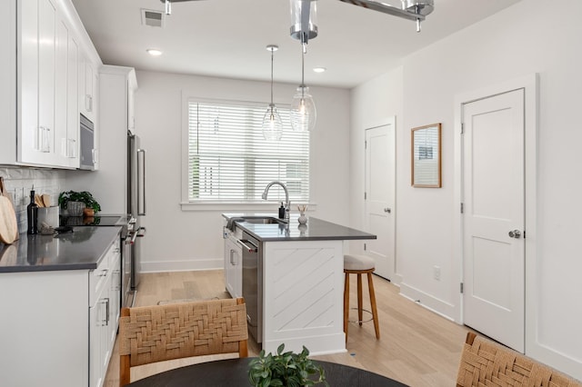 700 N Dupont Ave Unit 207, Madison, TN 37115 - kitchen featuring dark countertops, light wood-style flooring, stainless steel appliances, white cabinets, and an island with sink
