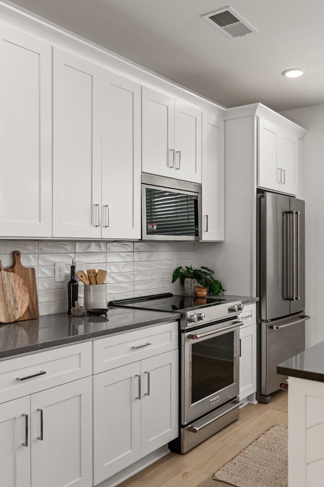 700 N Dupont Ave Unit 207, Madison, TN 37115 - kitchen with stainless steel appliances, white cabinets, light wood-style floors, tasteful backsplash, and recessed lighting
