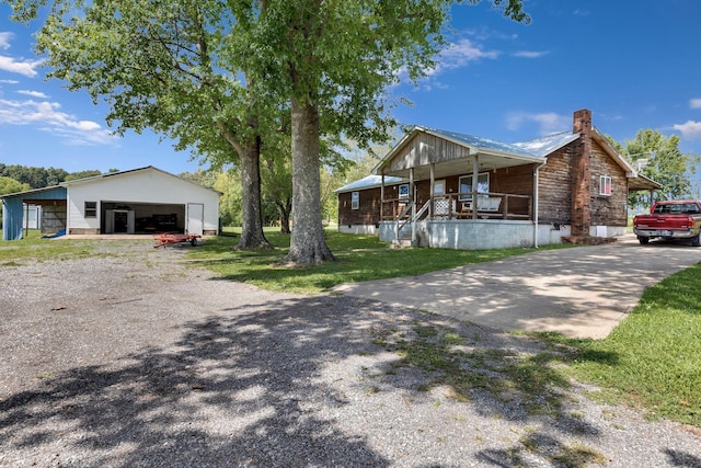 111 School St, Cumberland Furnace, TN 37051 - view of front of house featuring gravel driveway, a chimney, a porch, an outdoor structure, and a pole building